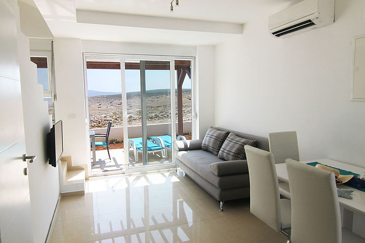 Wohnbereich mit Sofa und direktem Zugang zur Terrasse mit Meerblick