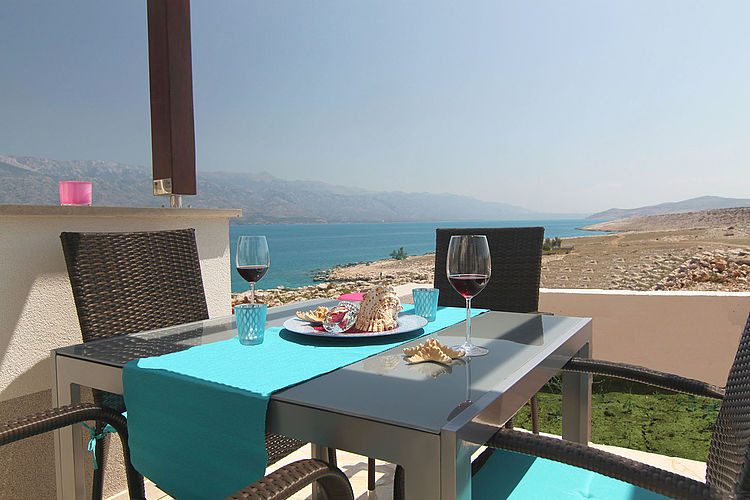 Gedeckter Tisch mit Weingläsern und türkisem Läufer, offener Blick auf Meer und Berge